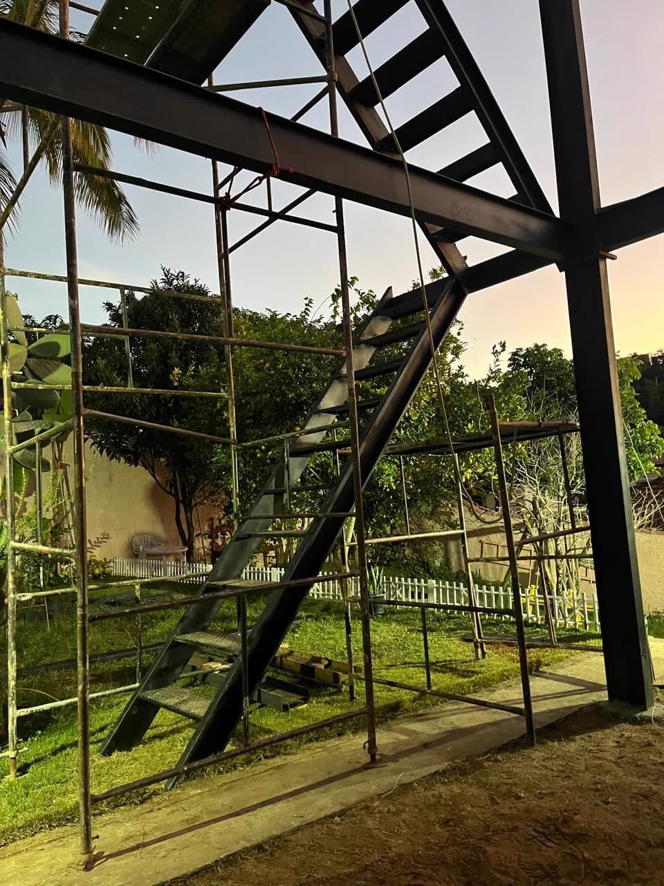 Estrutura do chalé ao entardecer, com escada e tesoura do telhado montadas
