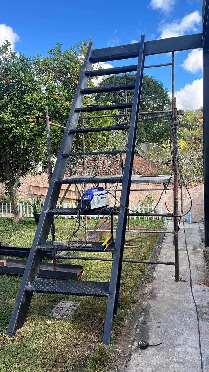 Escada metálica com degraus de chapa xadrez instalada na estrutura