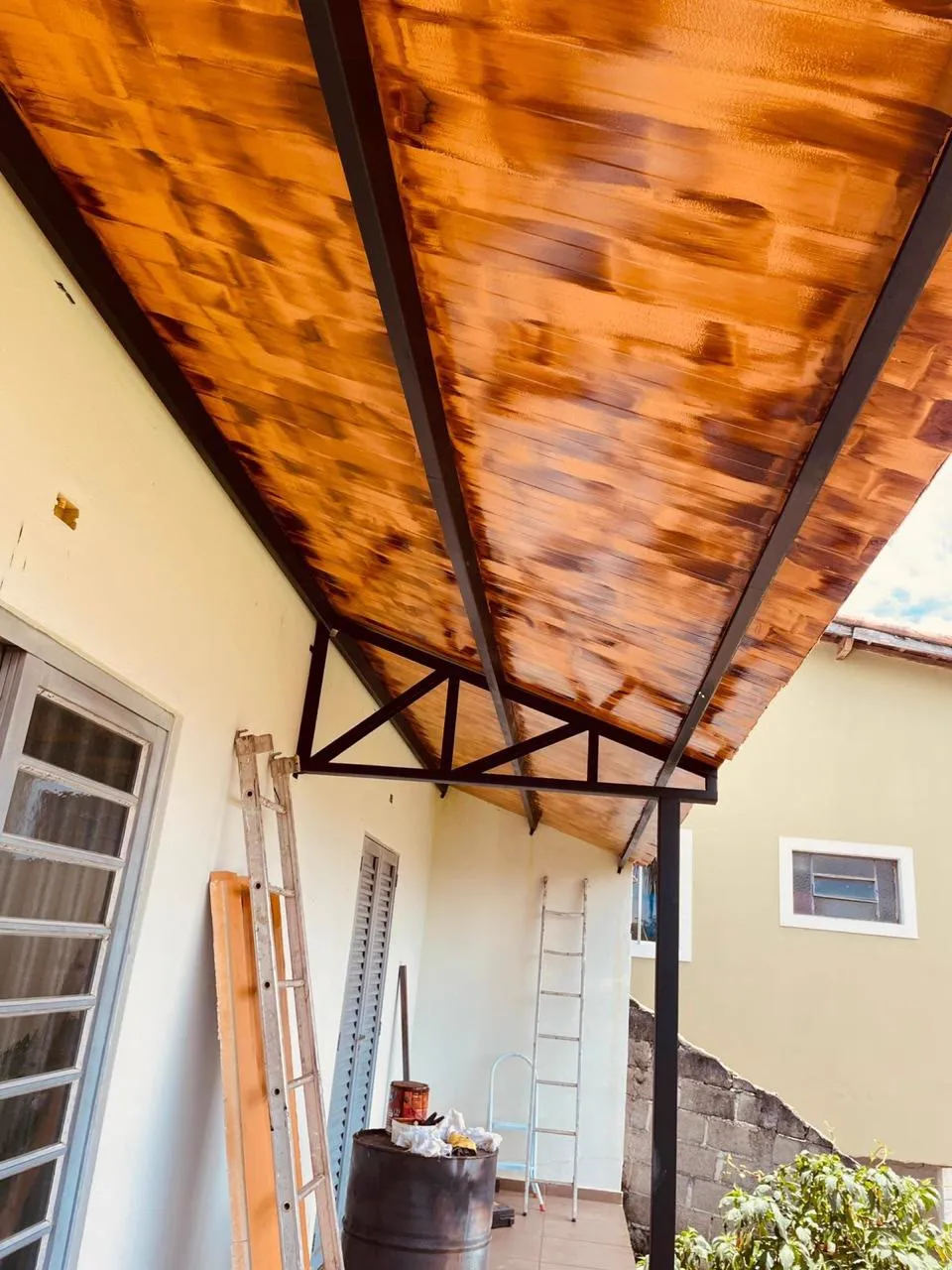 Detalhe da estrutura preta sustentando o forro de madeira